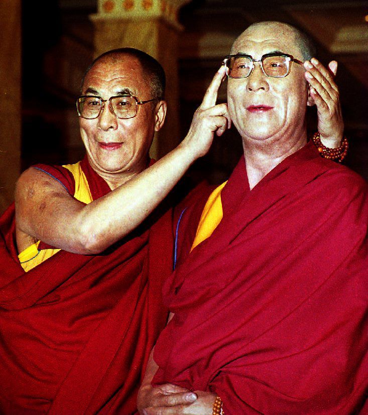 The Dalai Lama poses with his wax portrait in the